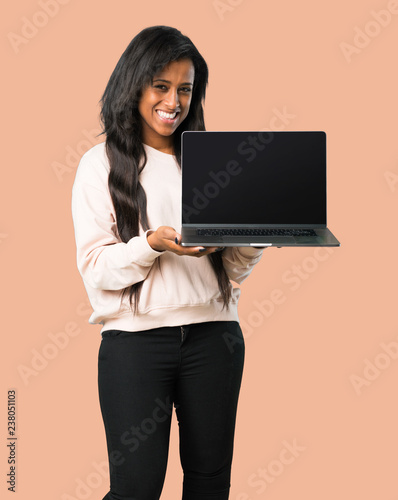 Young afro american woman showing a laptop on isolated brown background