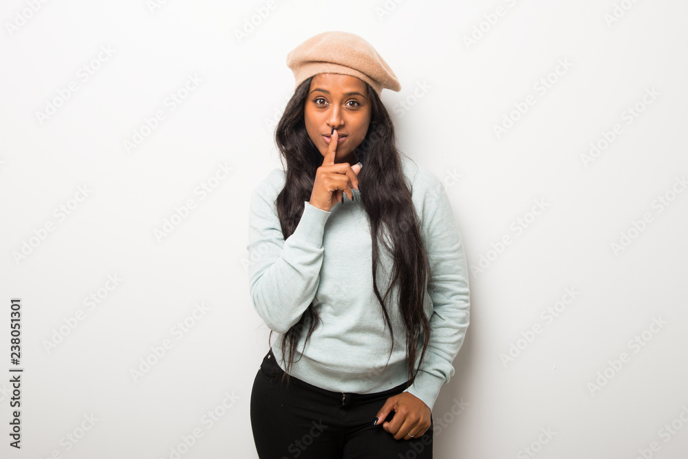 Young afro american woman on white wall showing a sign of silence gesture putting finger in mouth Young afro american woman on white wall showing a sign of silence gesture putting finger in mouth