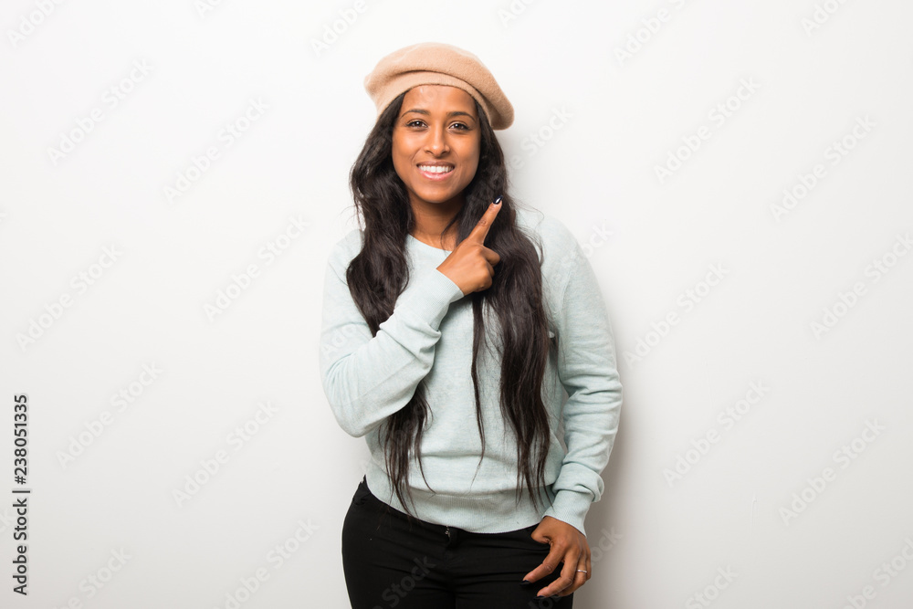 Young afro american woman on white wall pointing to the side with a finger to present a product Young afro american woman on white wall pointing to the side with a finger to present a product