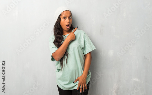 Young afro american woman on textured background surprised and pointing side