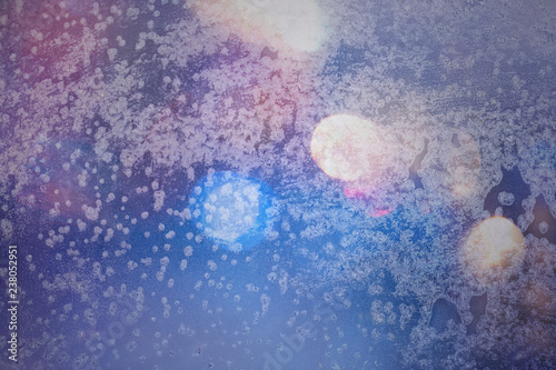 Fototapeta Naklejka Na Ścianę i Meble -  Winter background in soft pastel colors. Frost and snowflakes on the window. Multicolored bokeh with blur. Glare through glass. Background for holiday greetings with winter theme.
