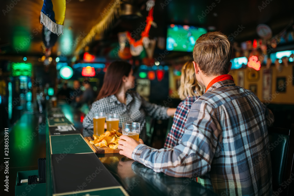 Naklejka premium Fans with glasses of beer at counter in sports bar