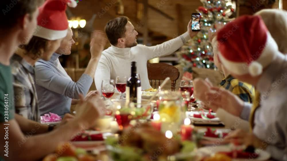 Man doing video translation of family Christmas dinner on his smartphone Man doing video translation of family Christmas dinner on his smartphone