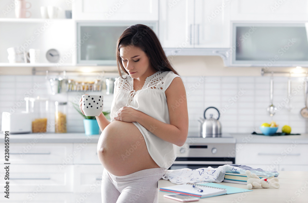 Pregnant woman preparing baby clothes for maternity hospital in kitchen Pregnant woman preparing baby clothes for maternity hospital in kitchen