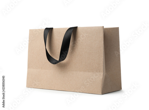 Paper shopping bag with ribbon handles on white background. Mockup for design photo