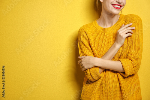 Beautiful young woman in warm sweater on color background. Space for text