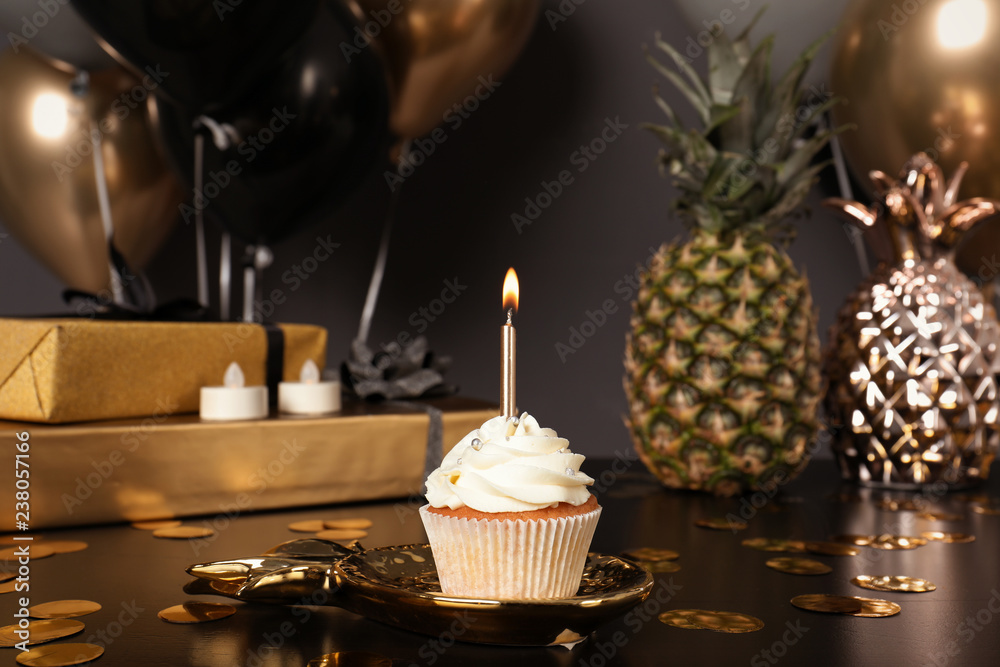 Cupcake with candle and blurred balloons on background
