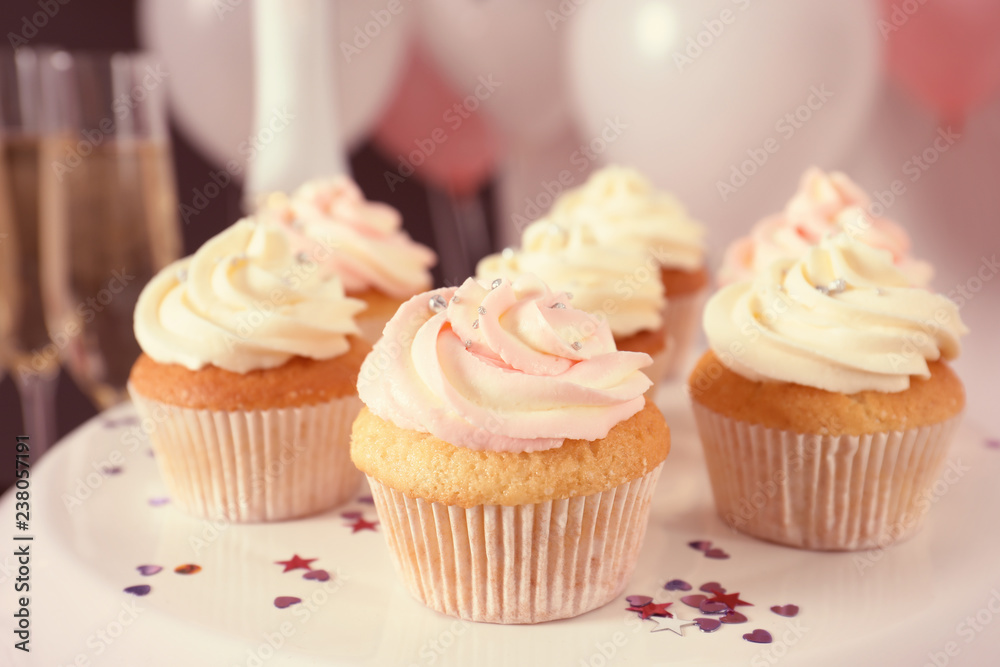Stand with cupcakes and blurred balloons on background, closeup