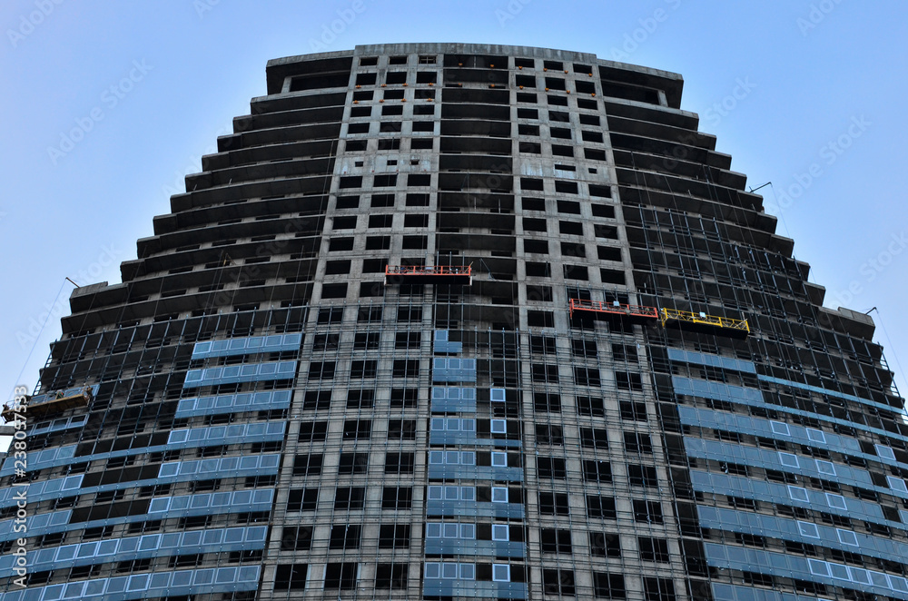 Construction workers in mobile hydraulic construction platform. Repair of the glass facade of the building Construction workers in mobile hydraulic construction platform. Repair of the glass facade of the building