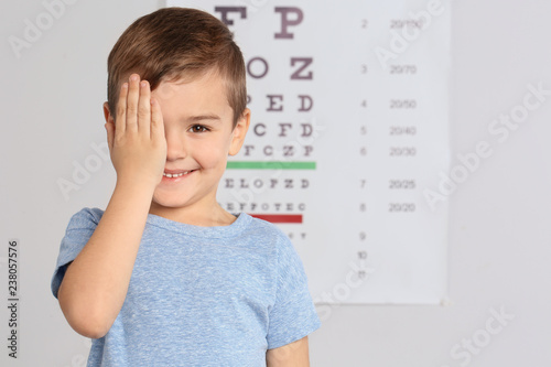 Cute little boy visiting children's doctor, space for text. Eye examination photo