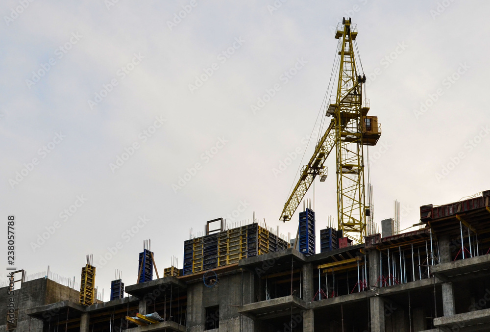 Construction of a high-rise building with a crane. Building construction using formwork. The construction crane and the building against the blue sky. Construction of a high-rise building with a crane. Building construction using formwork. The construction crane and the building against the blue sky.