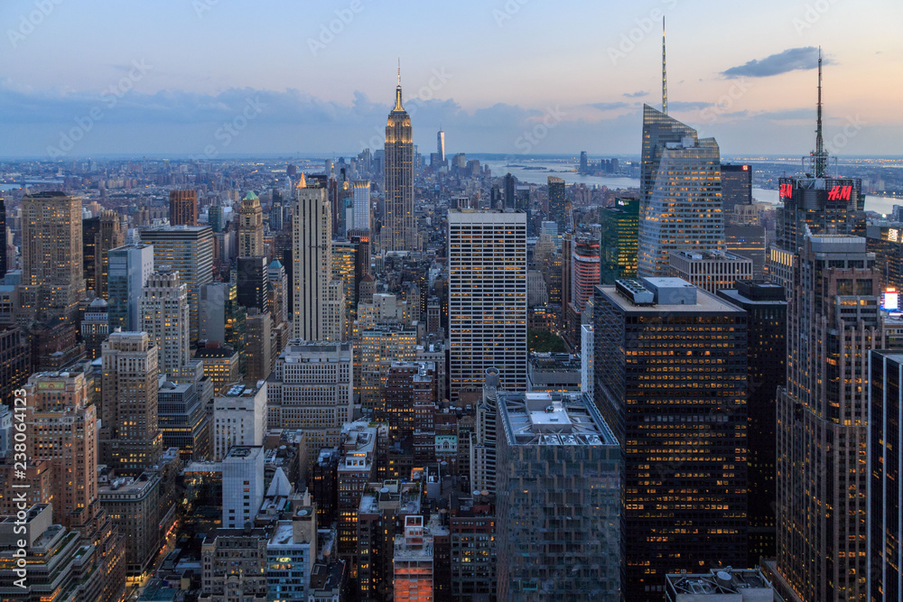 Fototapeta premium NEW YORK CITY, NY - AUGUST 20, 2014: Manhattan downtown skyline with illuminated Empire State Building and skyscrapers at sunset