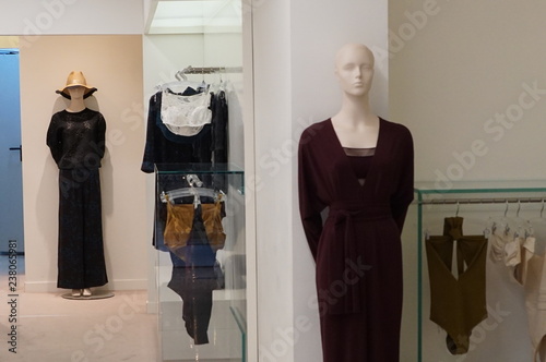 mannequin in dark red dress and dresses around