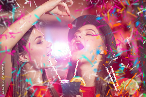 Confetti party. Two young girls lesbians at a party in the club are holding cocktail cherries.