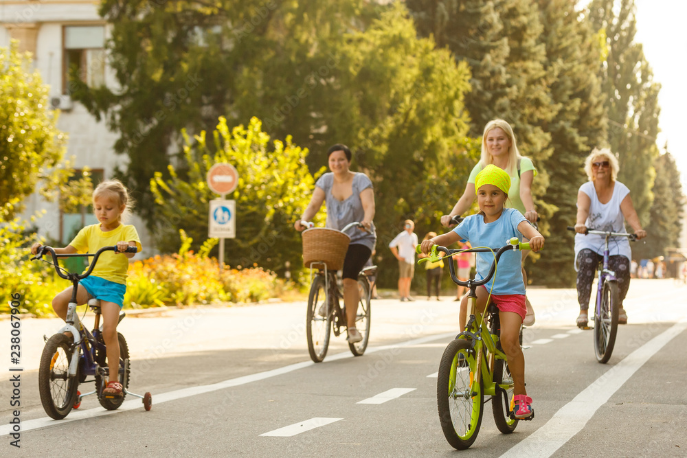 Fototapeta premium Theme family active sports outdoor recreation. A group of people is a big family of 6 people standing posing on mountain bikes in a city park on a road on a sunny day in autumn.