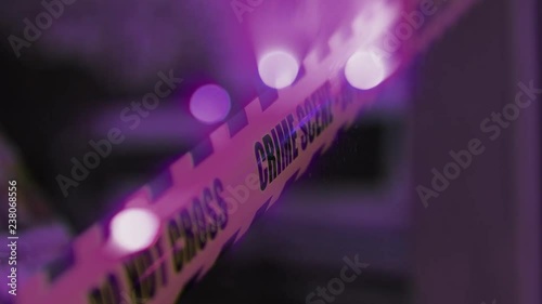 Violet color cast over police scene do not cross sign on the window of a store where murder thief has took place - reflection of blue siren lights defocused in the window
