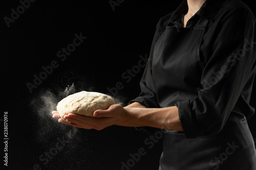 Chef, baker prepares bread. Flour freezing flour in the air. Advertising photo, on a black background, for design. Horizontal