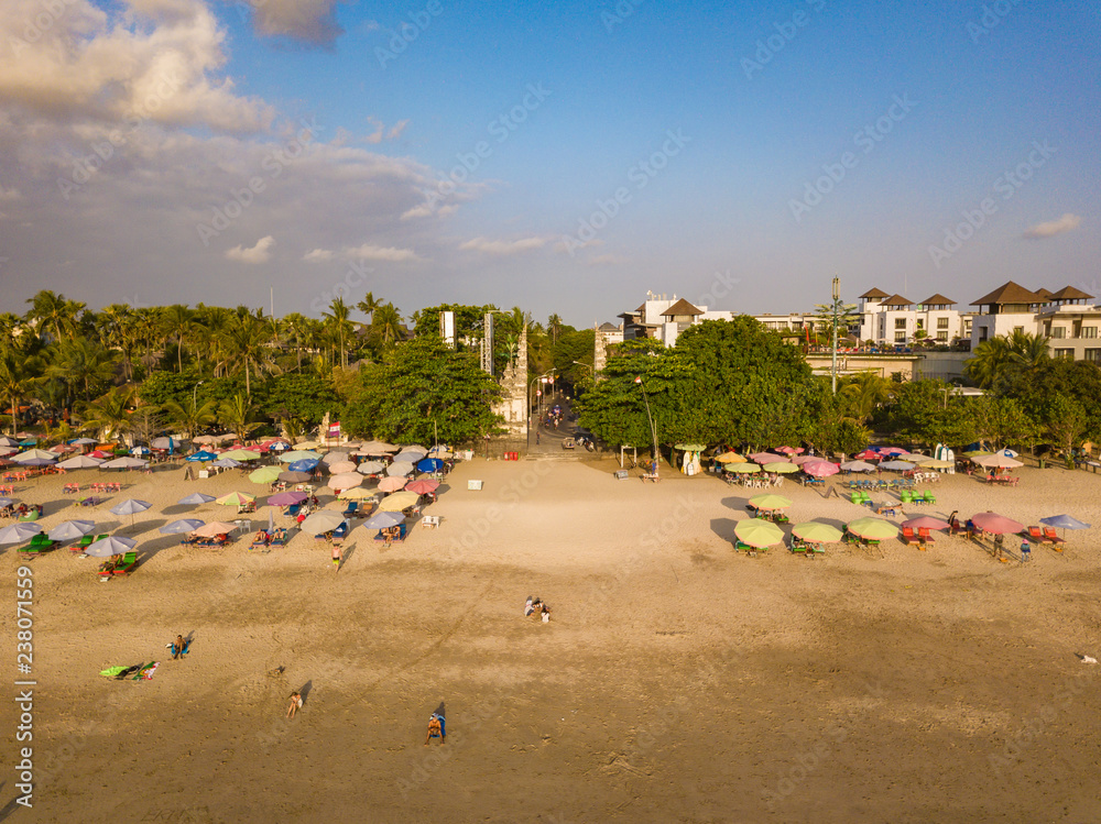 KUTA, BALI / INDONESIA - OCTOBER 25, 2018: Aerial view of Kuta town and beach with sun umbrellas lined up on the sand