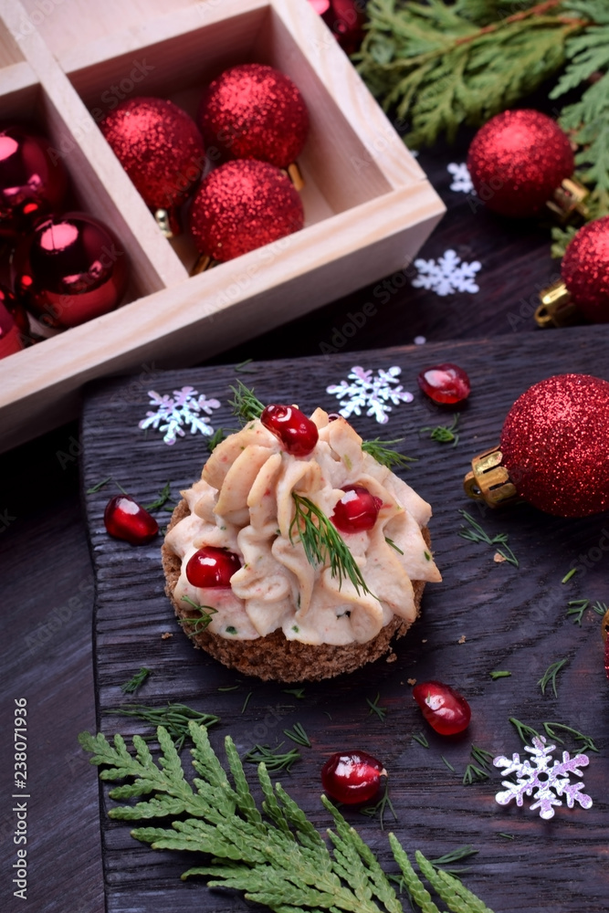 Canape shaped as a Christmas tree with pate garnished with pomegranate and dill surrounded by Christmas decorations
