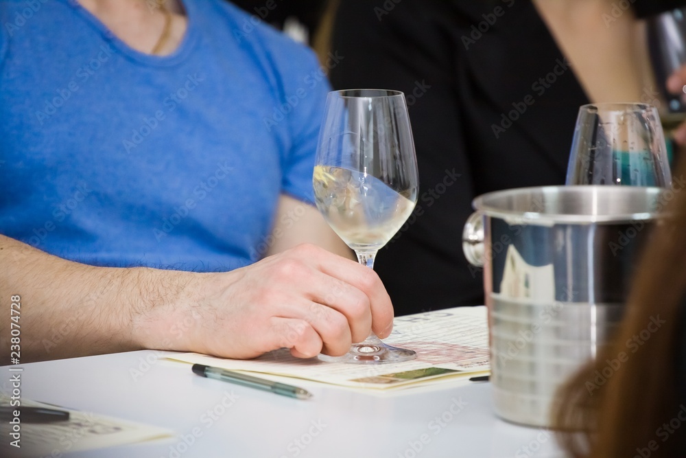 man's hand mixing white wine sauvignon blanc in a wineglass during wine testing in a wine shop man's hand mixing white wine sauvignon blanc in a wineglass during wine testing in a wine shop
