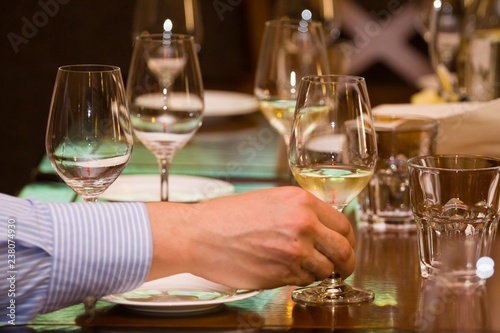 man's hand holds a wineglass with white wine during wine testing in a restaurant