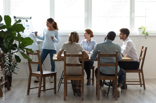 Five businesspeople gathered together for business training attentive listening mixed race coach. Company member prepared financial report in charts diagrams on increasing profits and reducing costs