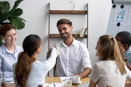 Successful businesspeople gathered together in office boardroom for negotiate and discuss new project greeting shaking hands. Company executive manager welcoming newcomer new worker female handshaking photo