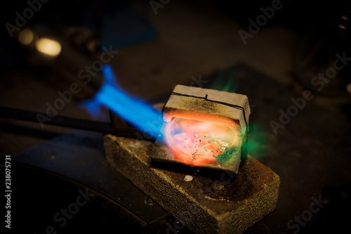 Jeweler melts with flame silver or gold on old workbench