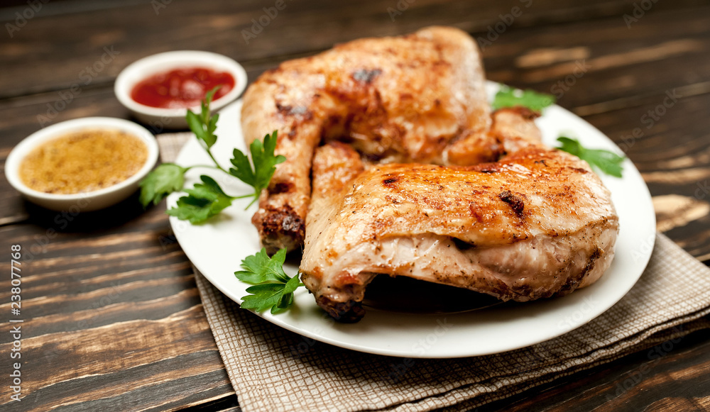 Chicken legs in a plate with mustard and ketchup on a wooden background. Chicken legs in a plate with mustard and ketchup on a wooden background.