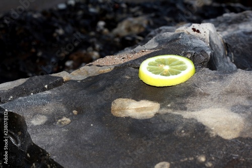 Un vaso de limonada sobre una roca, rodajas de limon