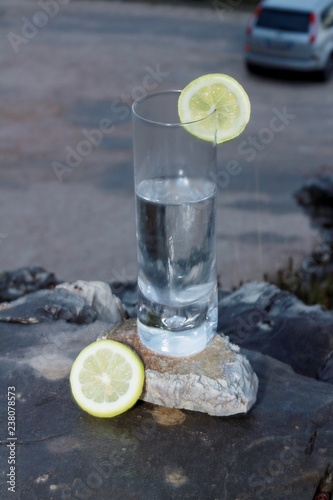 Un vaso de limonada sobre una roca, rodajas de limon