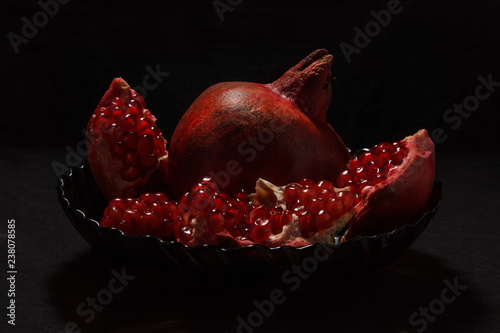 Appetizing red pomegranate in a plate on a dark background