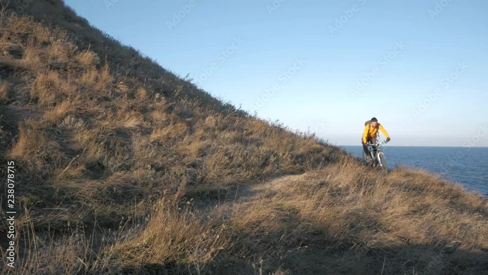 Young male bicycle rider travel on the hills in summer sunny day Young male bicycle rider travel on the hills in summer sunny day