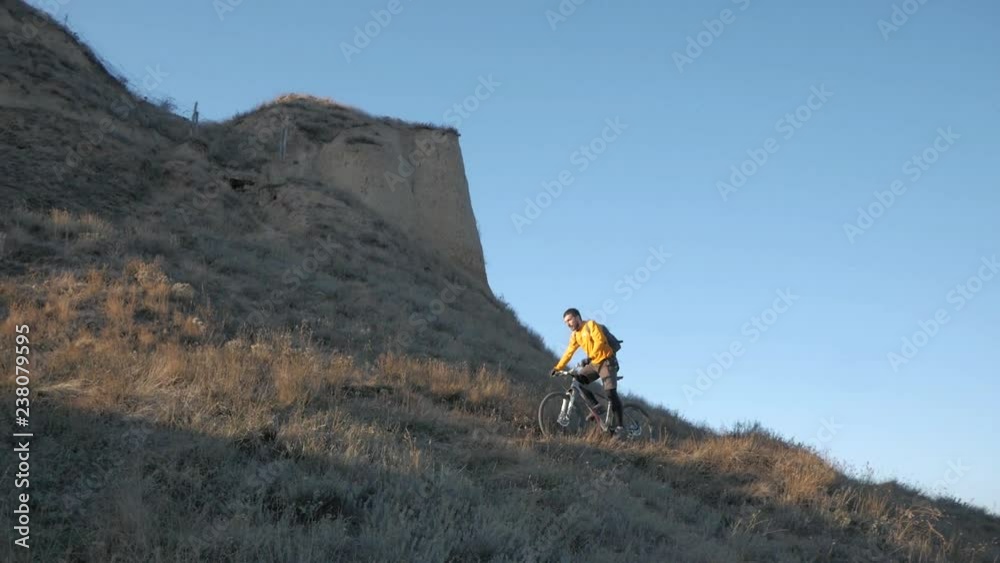 Young male bicycle rider travel on the hills in summer sunny day Young male bicycle rider travel on the hills in summer sunny day