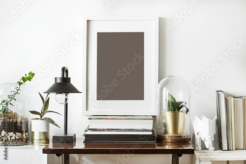 The room interior with white mock up frame, plants, wooden boxes, glass garden and stylish lamp. Concept of retro shelfie. 