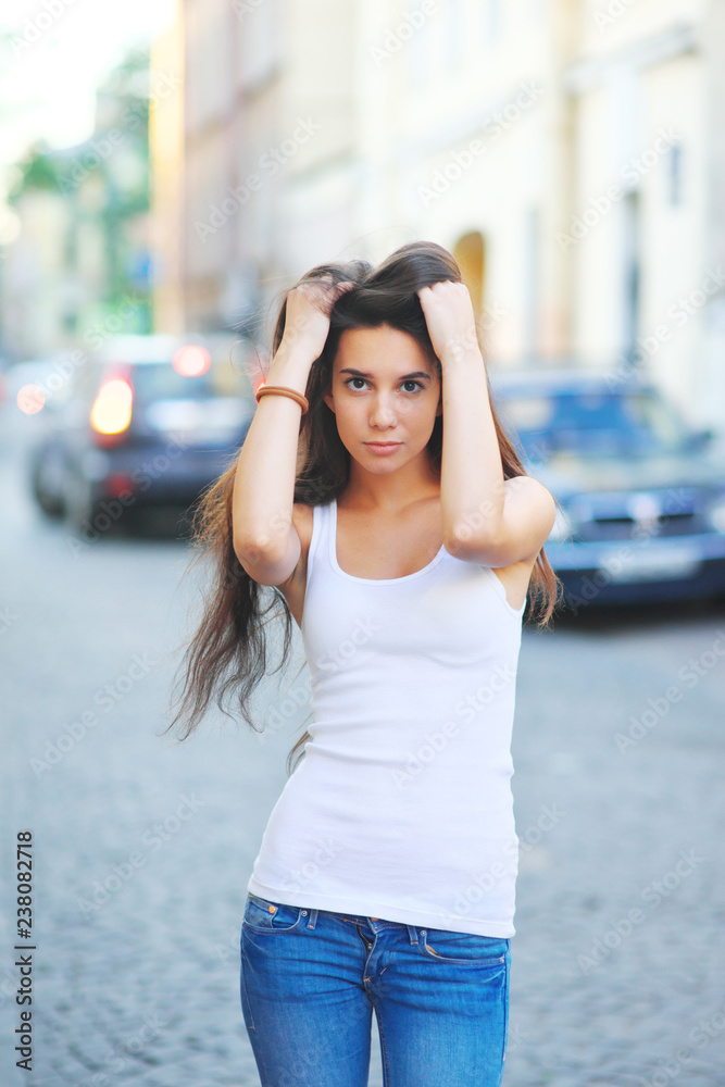 Hipster girl wearing blank white t-shirt and jeans posing against street road, minimalist urban clothing style, mockup for tshirt print store