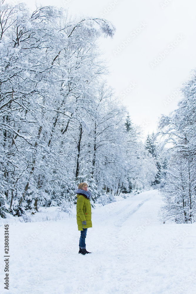 A young woman is walking through the winter forest