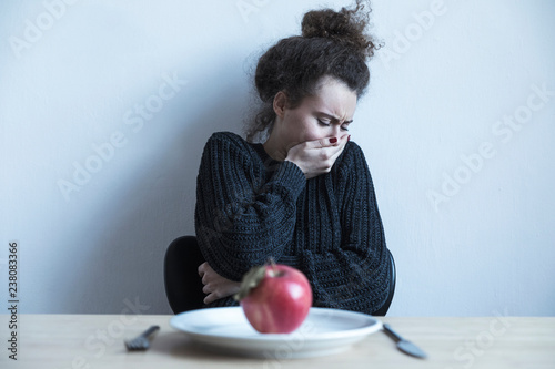Bilde på lerret Young woman with anorexia and depression sitting opposite the kitchen table