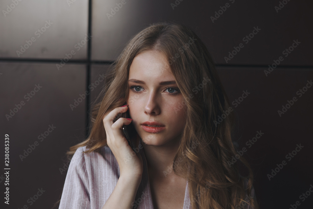 Unhappy teen girl looks at her smartphone experiencing anxiety and sad.