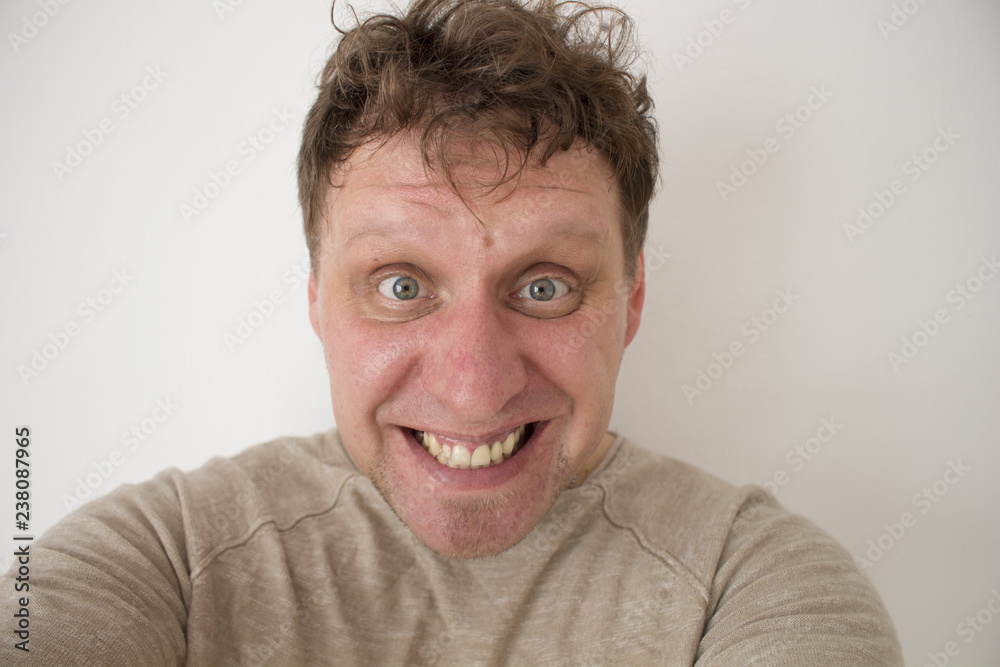 Joyfully laughing young man. Scoffs his teeth. Mad look into the camera. Joyfully laughing young man. Scoffs his teeth. Mad look into the camera.