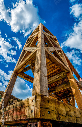 Wooden mine headframe against blue sky and clouds