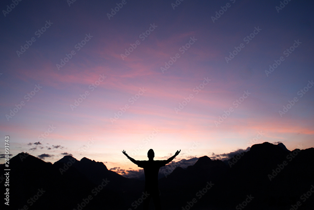 silhouette of a man on top of mountain at sunset