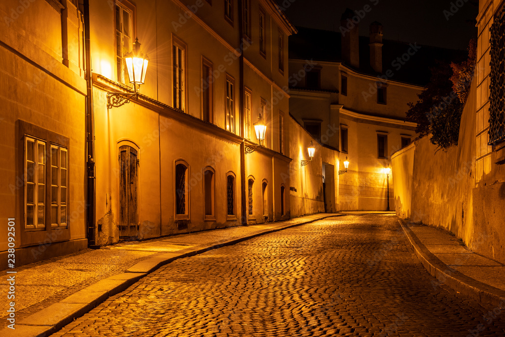 Narrow cobbled street in old medieval town with illuminated houses by vintage street lamps, Novy svet, Prague, Czech Republic. Night shot.