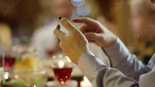 Family members texting in text messengers on smartphones by Christmas table, close up on hands