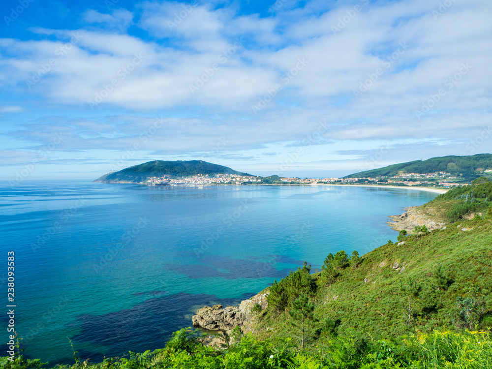 Paisaje bucólico de la Costa de Finisterre con el agua transparente azul y el verde de la costa. Verano de 2018