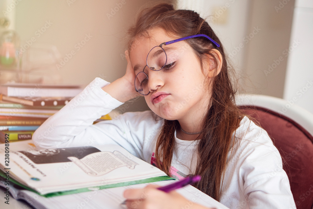 Bored little girl at home. Cute child doing homework. Modern education, communication Bored little girl at home. Cute child doing homework. Modern education, communication