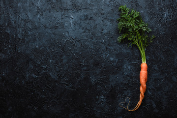 Healthy food concept. Fresh organic carrot with heart shape on black background top view. With copy space.