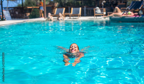 Beautiful young woman swimming in a pool while smiling © Marko