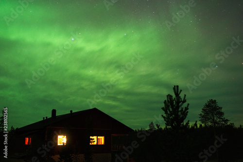 Night sky with Aurora Borealis above country house. © ekim