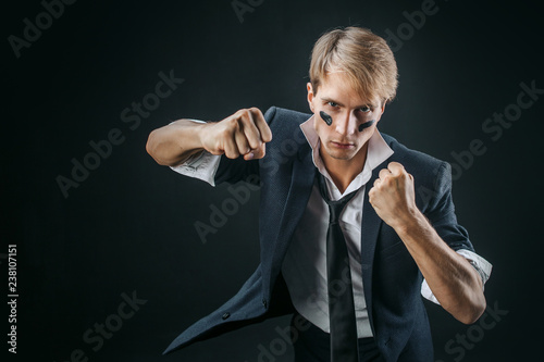 A young man in a business suit rolled up his sleeves and Boxing. Aggressive business, concept. Businessman